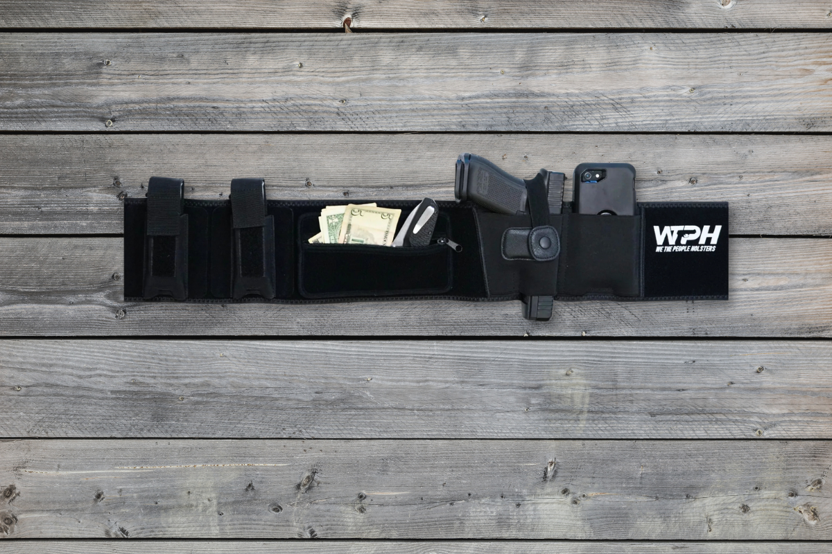 We The People belly band holster laid out on wooden deck so you can see it holds phone, money, gun, magazines.